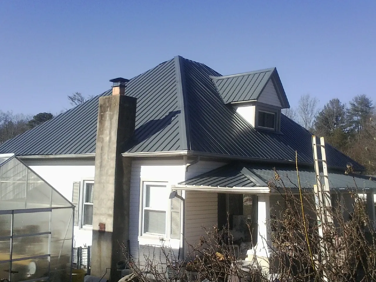 Dark blue standing seam metal roof on a white farmhouse with dormer — Slate & Tile Roof Repair by Roofing Brothers in Vantage