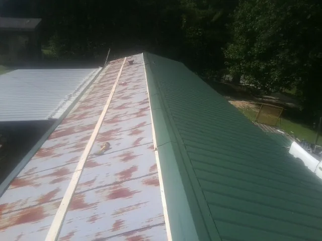 Old rusted panels beside newly installed green metal roofing — Wind Damage Roof Repair by Roofing Brothers in Vantage