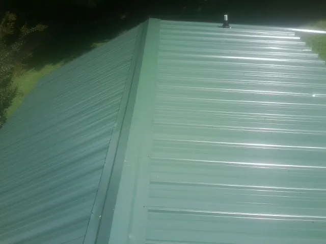 New green metal panels meeting at the ridge of a roof — Flat Roof Repair work by our crew in Vantage