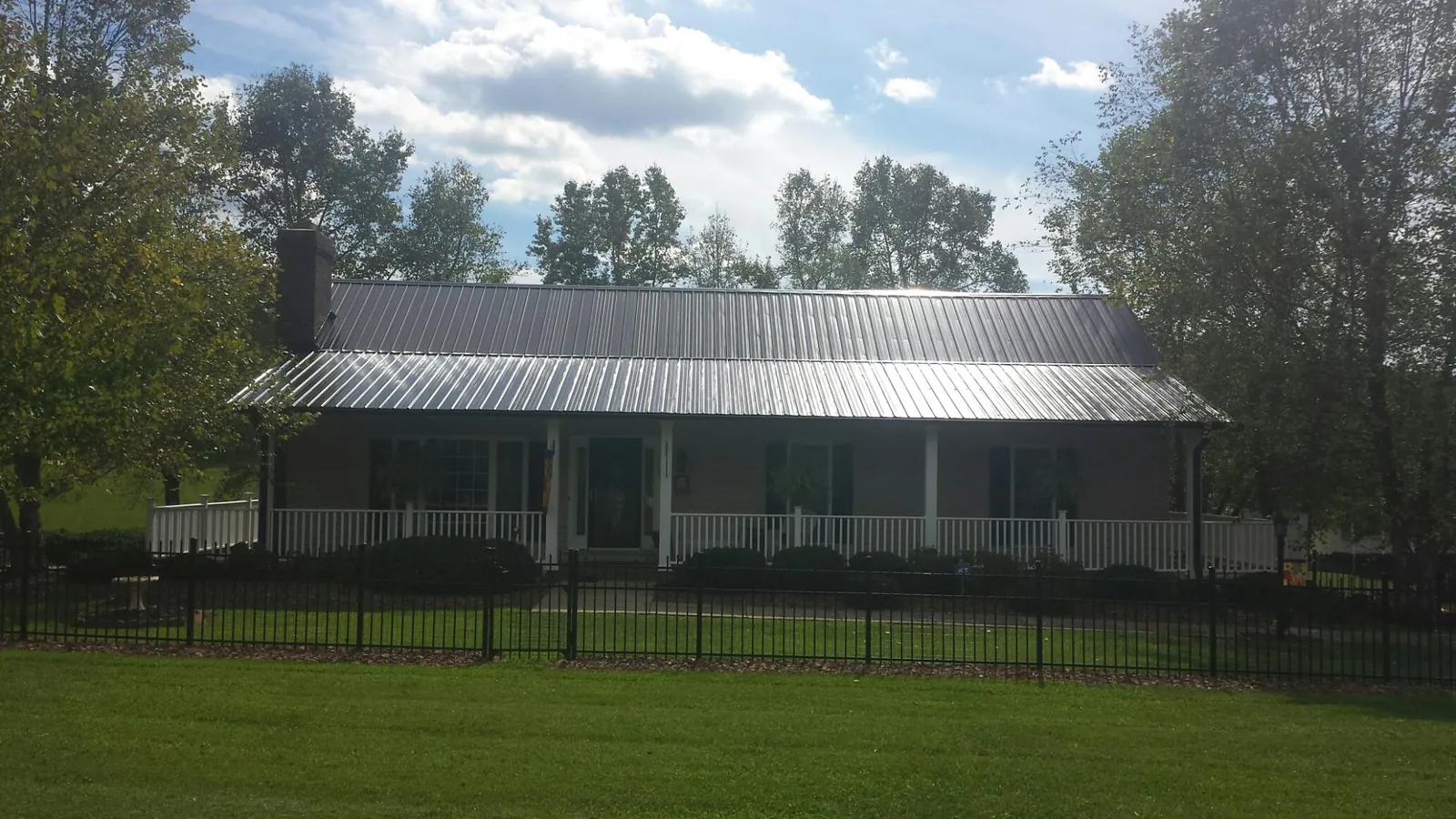 Gray metal roof on a brick ranch with a full width front porch — Gutter Guard Installation work by our crew in Vantage
