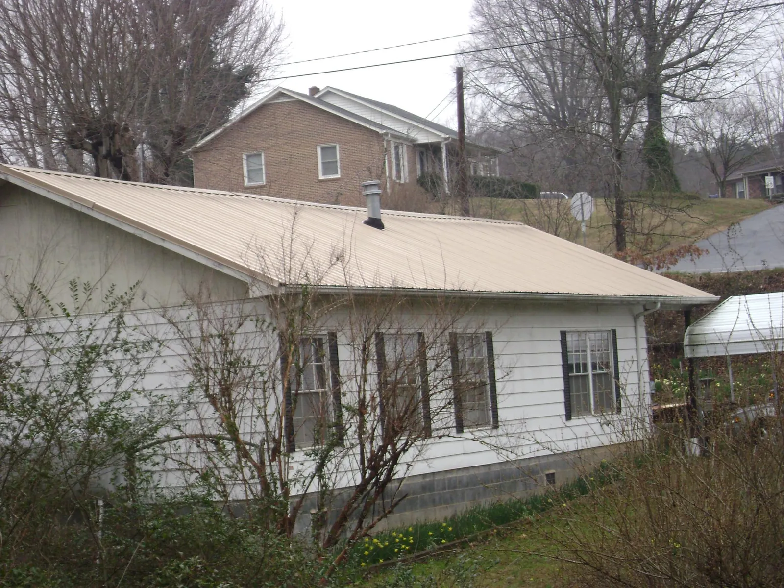 Tan metal roof on a white sided house set into a hillside — Commercial Roofing by Roofing Brothers in Vantage