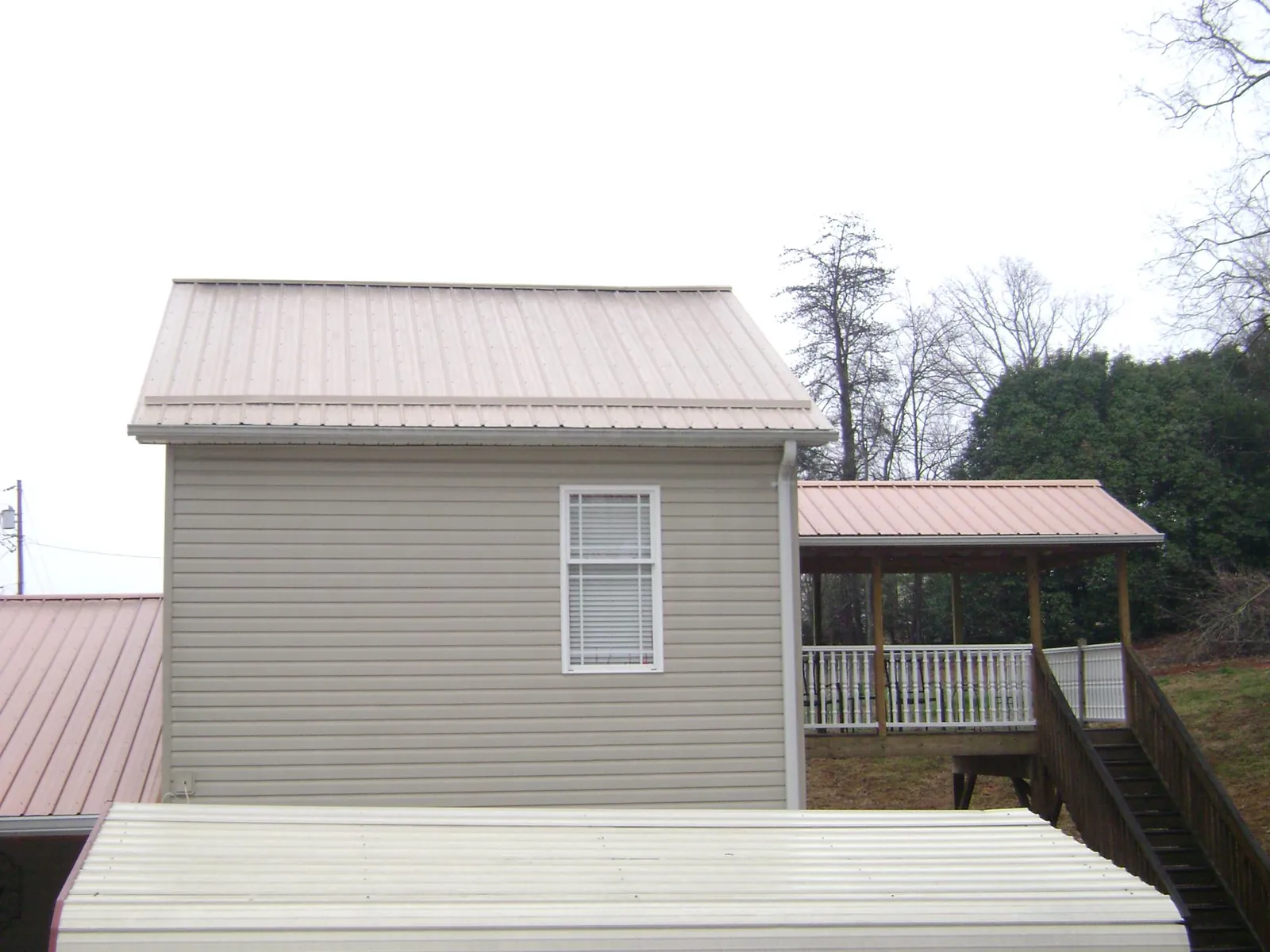 Tan metal roofs on a two story addition and attached porch, from a Roof Replacement job in Vantage