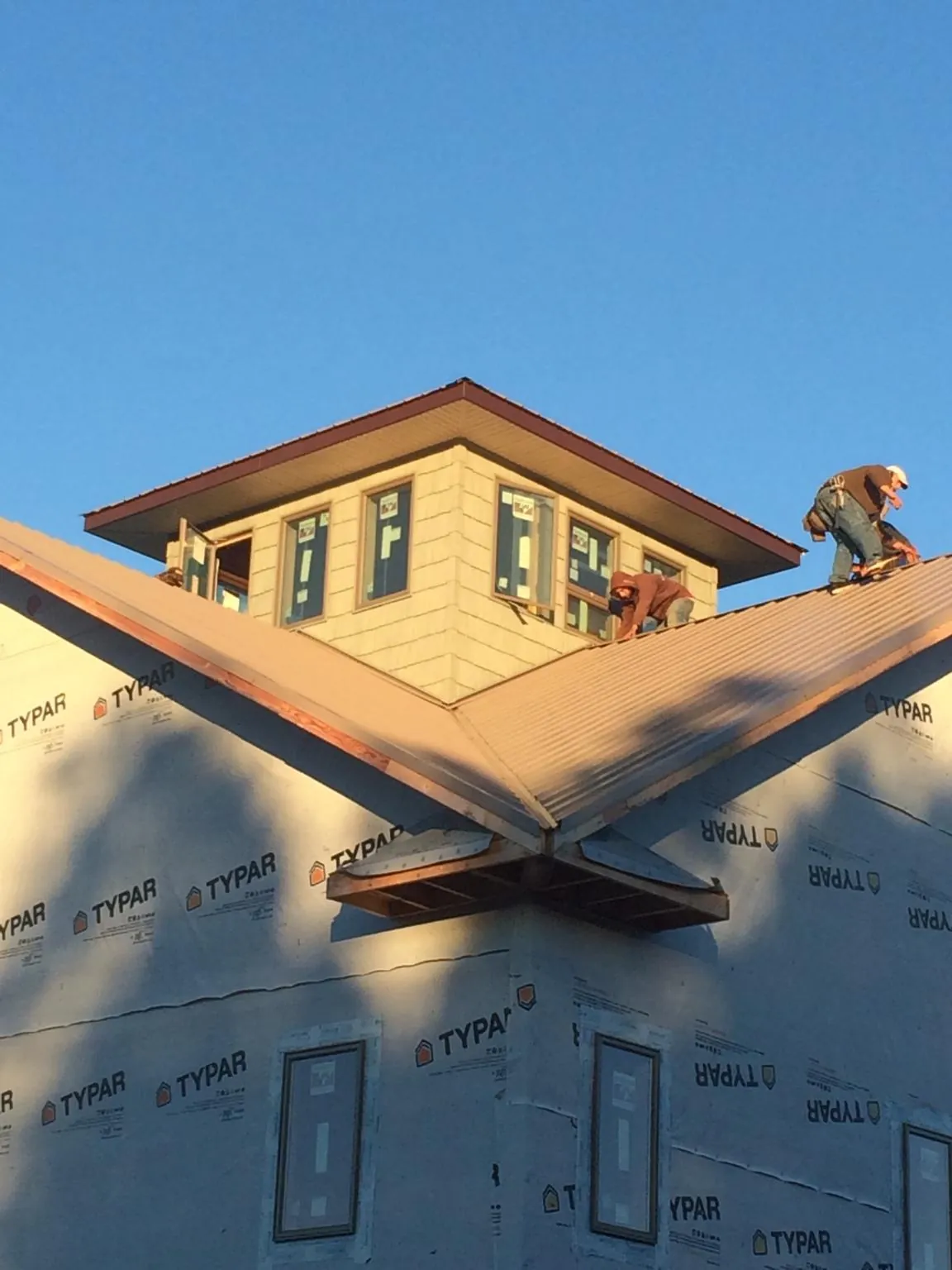 Roofers working around a rooftop cupola on a new metal roof at sunset — Roof Waterproofing in Vantage by Roofing Brothers